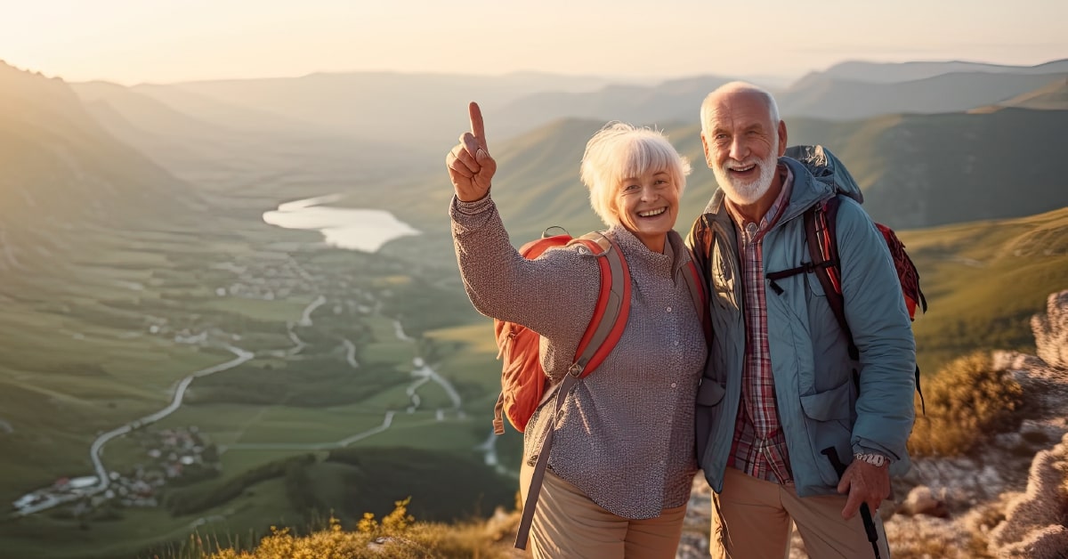 Dva usmívající se důchodci na turistice na horách